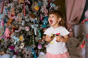 un' poco ragazza giochi vicino il Natale albero foto