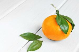 mandarino con foglie su un tavolo bianco foto