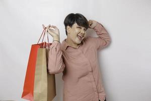 un' contento giovane donna è indossare rosa camicia e Tenere regali o shopping Borsa. foto