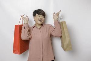 un' contento giovane donna è indossare rosa camicia e Tenere regali o shopping Borsa. foto