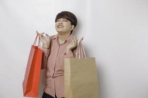 un' contento giovane donna è indossare rosa camicia e Tenere regali o shopping Borsa. foto