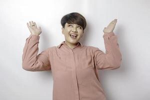 eccitato asiatico donna indossare rosa camicia puntamento a il copia spazio sottosopra suo, isolato di bianca sfondo foto
