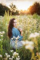 bella ragazza che cammina sul campo in estate con fiori di campo. foto