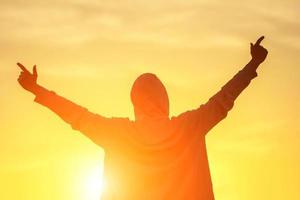 un' uomo nel il leggero di il tramonto con il suo mani su, il concetto di successo, la libertà e gioia foto