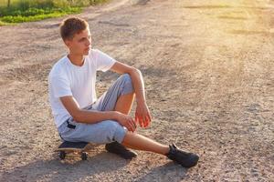 allegro tipo seduta su un' skateboard su il strada su un' soleggiato giorno foto