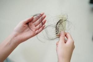 la donna asiatica ha problemi con la caduta dei capelli lunghi attaccata alla spazzola del pettine. foto