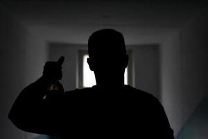 silhouette di tipo con bottiglia di birra. uomo nel buio Spettacoli alcol. uomo nel davanti di porta spioncino. sconosciuto persona. foto