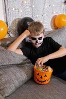 il bambino prende su il caramella a partire dal il secchio per Halloween foto