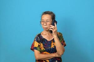anziano donna utilizzando mobile smartphone tecnologia comunicazioni su sfondo. foto