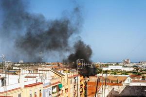 nero Fumo a partire dal un' fuoco diffusione al di sopra di il città contro blu cielo foto