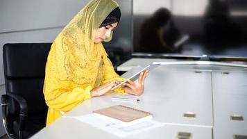 un' donna d'affari è utilizzando un' tavoletta per opera e lei è stressato a sua scrivania. foto
