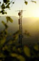 telecomunicazioni aeree al tramonto, la città sullo sfondo foto
