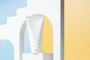 crema tubo con crema il branding concetto su concreto podio su blu e giallo sfondo. cosmetico cura della pelle Prodotto vuoto plastica pacchetto. bianca senza marchio lozione, balsamo, mano crema, dentifricio modello foto