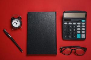 maschio nero bloc notes a sfera penna e calcolatrice, piccolo allarme orologio e bicchieri foto
