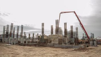 un' bellissimo tiro di un' enorme fabbrica costruzione con poli e gru. cassaforma e calcestruzzo scrosciante foto