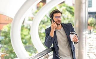 il uomo Tenere un' tazza di caffè e utilizzando un' smartphone e parlando con il suo amico mentre lui in attesa il suo amico a il aeroporto. foto