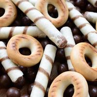 un' lotto di croccante dolce tubuli, cioccolato fusione palle e giallo bagel menzogna su un' di legno superficie. vicino su Visualizza foto