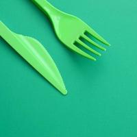 monouso plastica posate verde. plastica forchetta e coltello menzogna su un' verde sfondo superficie foto