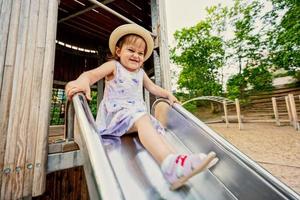 bambino ragazza scivoli nel figli di terreno di gioco giocattolo impostato nel pubblico parco. foto