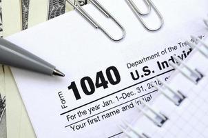 il penna, taccuino e dollaro fatture è bugie su il imposta modulo 1040 noi individuale reddito imposta Restituzione. il tempo per pagare le tasse foto
