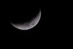 mezzaluna Luna nel buio inverno cielo con nero sfondo foto