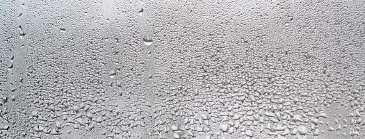 struttura di un' far cadere di pioggia su un' bicchiere bagnato trasparente sfondo. tonica nel grigio colore foto