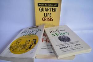 blitar, Indonesia - ottobre 9 ° 2022 sfocatura effetto di parecchi libri intitolato trimestre vita crisi, tera filosofia e psicologia di i soldi isolato su bianca sfondo foto