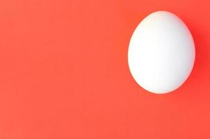 uno bianca uovo su un' luminosa rosso sfondo foto