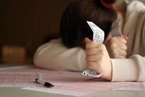 un' triste giovane ragazza soffre a partire dal un' perdita dopo guardare il sfortunato risultato di il lotteria gioco d'azzardo. il concetto di perdente il lotteria e trascorrere i soldi foto