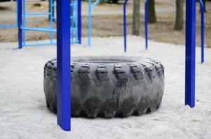 un' grande nero pneumatico contro un' strada gli sport campo per formazione traccia e campo Atletica e crossfit. all'aperto atletico Palestra attrezzatura. macro foto con selettivo messa a fuoco e sfocato sfondo