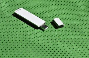 un' moderno portatile USB Wi-Fi adattatore è posto su il verde abbigliamento sportivo fatto di poliestere nylon fibra foto