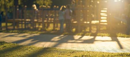 sfocatura terreno di gioco con bambini di il luminosa luce del sole nel parco astratto sfondo. foto
