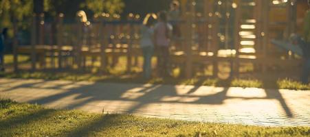 sfocatura terreno di gioco con bambini di il luminosa luce del sole nel parco astratto sfondo. film tono effetto. foto