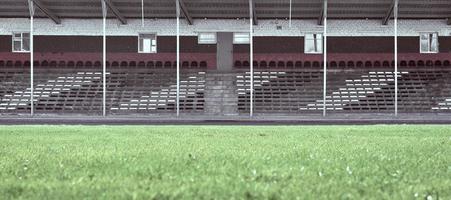 vuoto pubblico posti a sedere a il stadio. nel il primo piano è un' verde campo nel sfocatura. foto