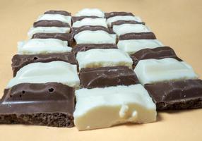 fette di nero e bianca cioccolato su un' biege sfondo. vario cioccolatini su il tavolo. foto