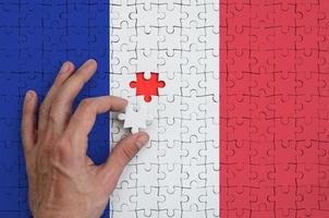 Francia bandiera è raffigurato su un' puzzle, quale il dell'uomo mano completa per piegare foto