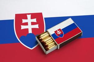slovacchia bandiera è mostrato nel un Aperto scatola di fiammiferi, quale è pieno con fiammiferi e bugie su un' grande bandiera foto