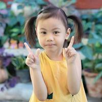 positivo affascinante 4 anni vecchio carino bambino asiatico ragazza, poco bambino in età prescolare bambino con adorabile trecce capelli sorridente guardare a telecamera. foto