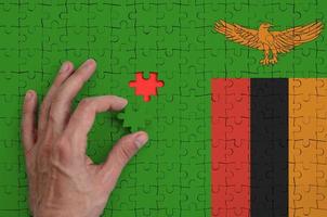 Zambia bandiera è raffigurato su un' puzzle, quale il dell'uomo mano completa per piegare foto