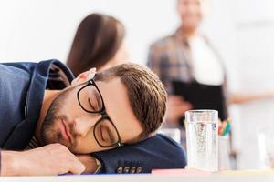 stanco uomo d'affari. stanco giovane uomo d'affari addormentato mentre seduta a il suo Lavorando posto e pendente il suo testa a il scrivania foto