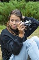 ritratto di un' bellissimo adolescenziale ragazza avendo divertimento con un' telecamera. un' ragazza prende immagini all'aperto con un vecchio telecamera. foto