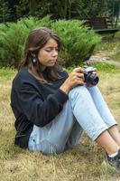 ritratto di un' bellissimo adolescenziale ragazza avendo divertimento con un' telecamera. un' ragazza prende immagini all'aperto con un vecchio telecamera. foto