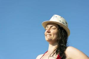 parte inferiore Visualizza di un' giovane donna nel un' cappello e un' costume da bagno contro il sfondo di un' blu cielo foto