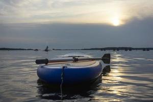 cenare asse, pagaia tavola con un' pagaia nel il tramonto leggero su il sfondo di acqua avvicinamento. cenare imbarco attrezzatura. foto