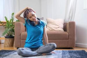 sorridente asiatico donna fare yoga spalla allungamento in linea classe a casa nel vivente camera. se stesso solitudine e allenarsi a casa durante covid19. foto