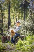 un' carino ragazzo è giocando con un' orso cucciolo nel il foresta. il di sole raggi avvolgere il spazio di il radura con un' ceppo. un' magico storia di interazioni per il libro. spazio per copiando. selettivo foto