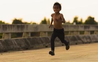 un' forte poco ragazzo corse lungo il ponte. foto