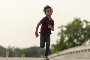 un' poco ragazzo corre lungo il ponte. foto