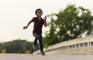 un' poco ragazzo corre lungo il ponte. foto