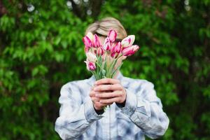 tipo detiene un' mazzo di tulipani Tenere loro nel davanti di lui foto